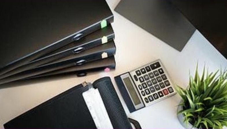 Carpetas, calculadora y planta sobre un escritorio